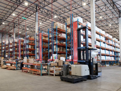 Forklift near packed goods in shelves for logistics at distribution warehouse