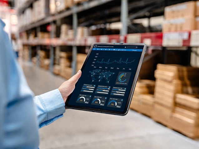 Businessman using digital tablet with warehouse management system dashboard on screen, monitoring inventory, delivery, and supply chain analytics in smart logistics distribution center