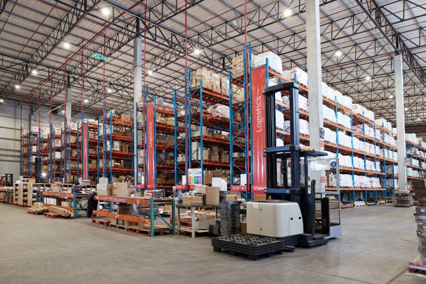 Forklift near packed goods in shelves for logistics at distribution warehouse